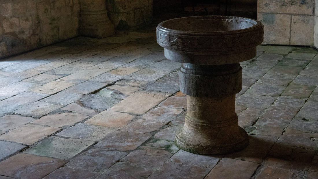 Fonts baptismaux de pierre sculptee poses sur les dalles usees d'une eglise ancienne