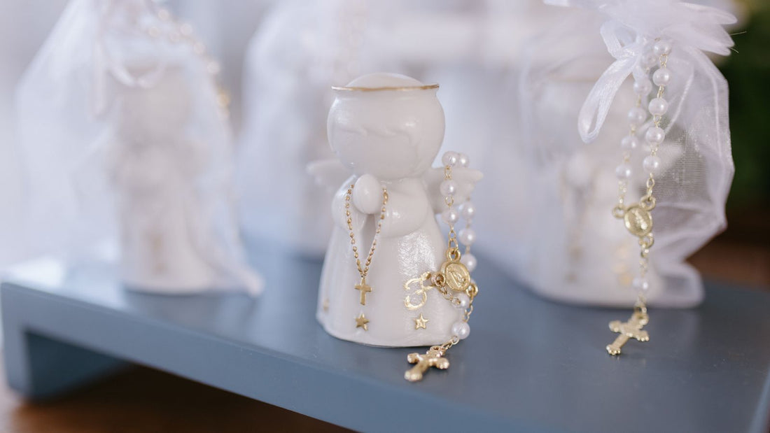 Chapelets dorés posés sur de petites figurines d’ange en céramique blanche, préparés pour être offerts.
